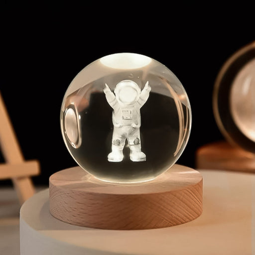 A glowing Moon Crystal Ball Lamp on a wooden base, casting a soft light in a dimly lit room.
