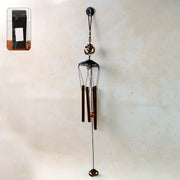 Metal wind chime with Om symbol hanging outdoors in a garden