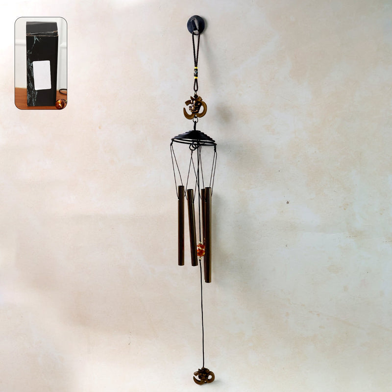 Metal wind chime with Om symbol hanging outdoors in a garden