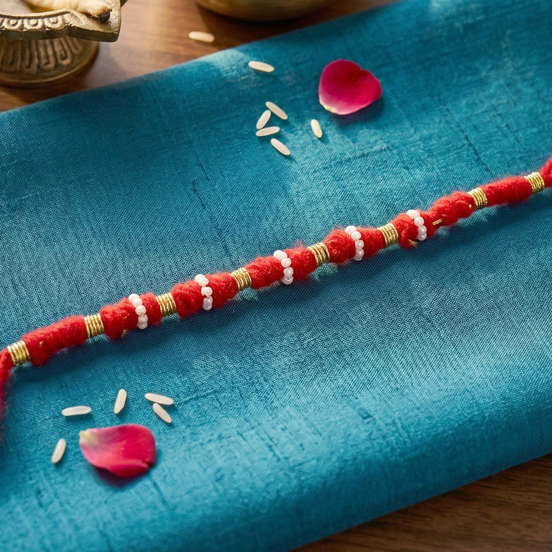 Traditional red rakhi featuring pearl and golden bead work