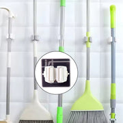 Single adhesive mop holder securely holding a mop on a wall.