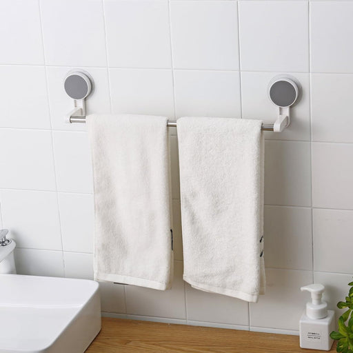 Self-adhesive towel rod mounted on bathroom wall holding hand towels