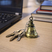 Detailed view of metal temple bell keychain hanging with spiritual design