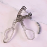 Transparent eyelash curler viewed from side angle showing smooth press