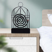 Decorative mosquito coil holder used outdoors on a patio table at dusk.