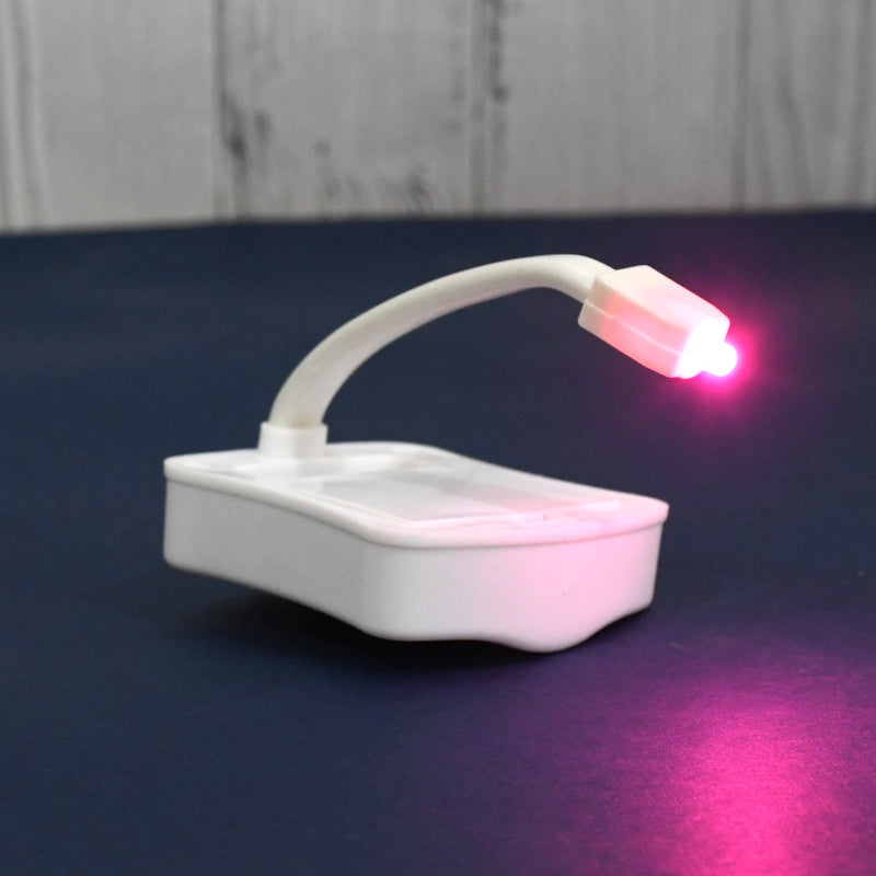 Hand holding the battery-operated LED toilet light, highlighting its portable design.