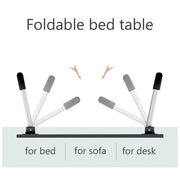 Individual using the portable bed desk for reading a book and taking notes in a relaxed setting.