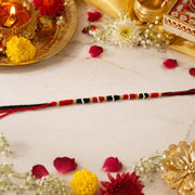 Close-up of traditional handmade red black thread rakhi with beads