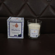 Hand holding a Blueberry Scented Candle, demonstrating its compact size.