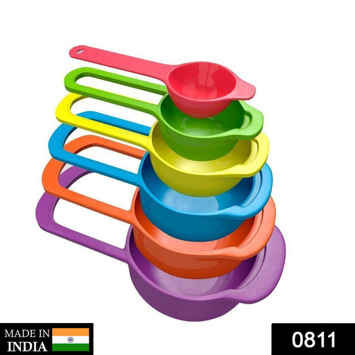 Stacked multi-colored plastic measuring spoons, held together by a ring, on a kitchen surface.