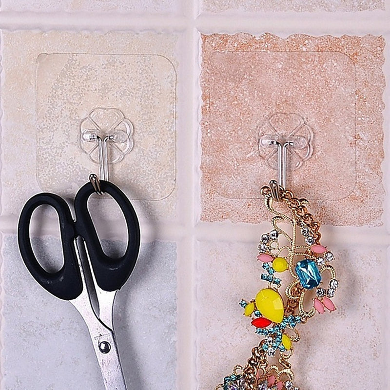 Pair of small stainless steel adhesive hooks on a white wall.