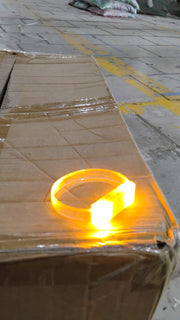 An LED running bracelet brightly glowing in a dark outdoor night environment.