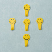 A set of five white self adhesive hooks displayed on a clean surface.