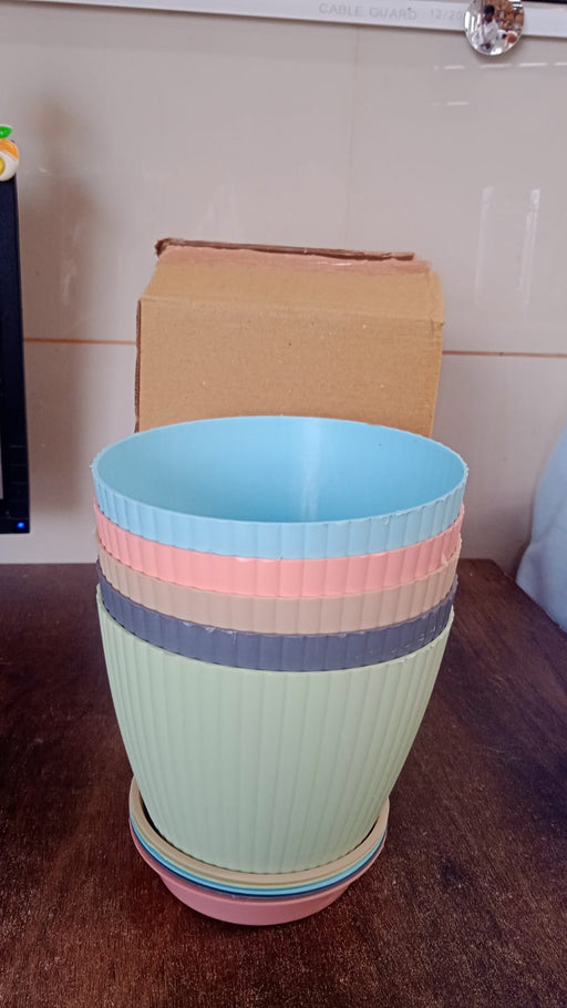 A set of five plastic flower pots with trays displayed on a shelf.