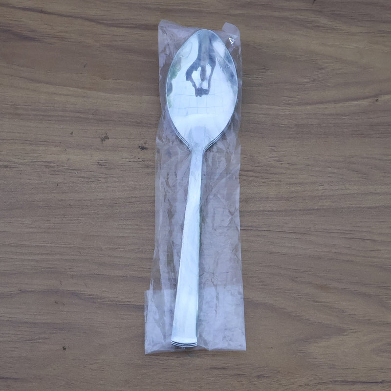 Stacked stainless steel dining spoons placed in a home kitchen setting