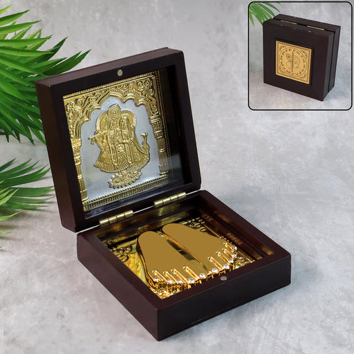 Elegant gold-finished Charan Paduka set displayed inside wooden box with Radha Krishna design