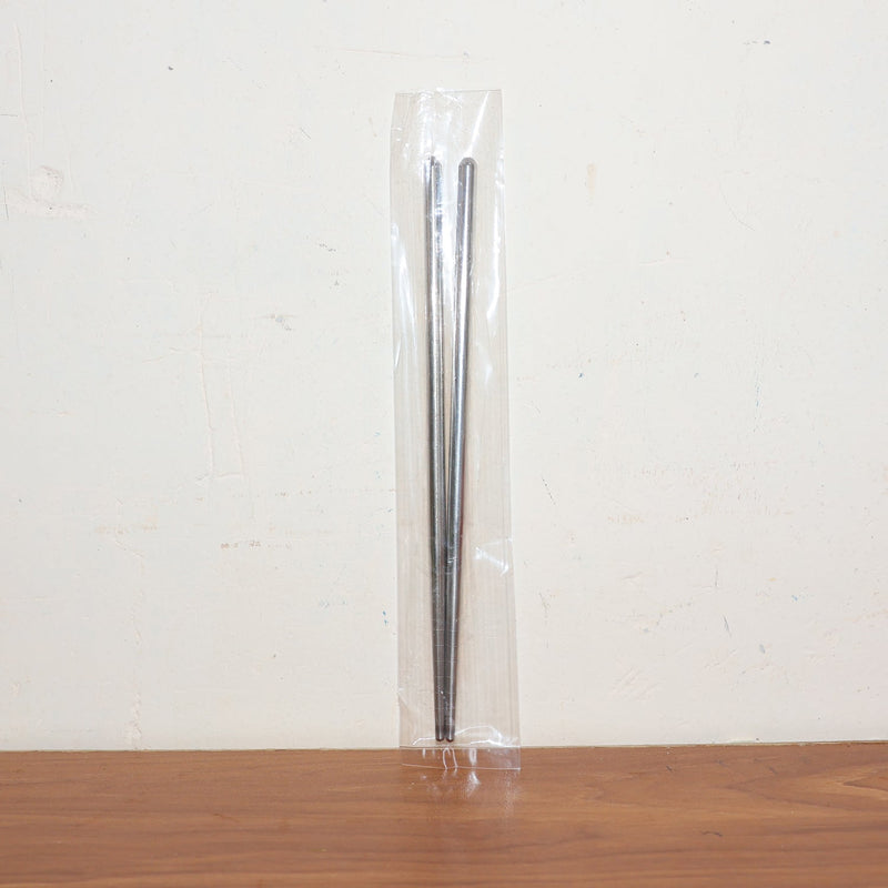 Stainless steel chopsticks actively used to pick up food during a meal.