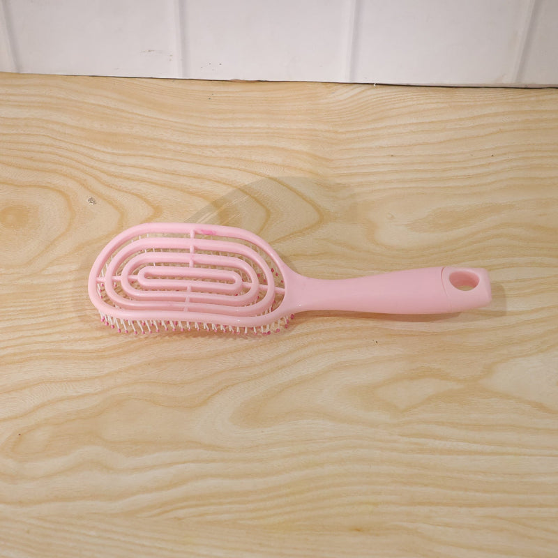 Woman brushing her hair with pink curved styling brush
