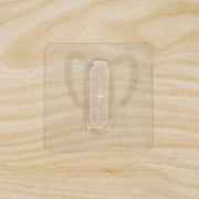 Close-up of transparent wall hook showing its adhesive pad