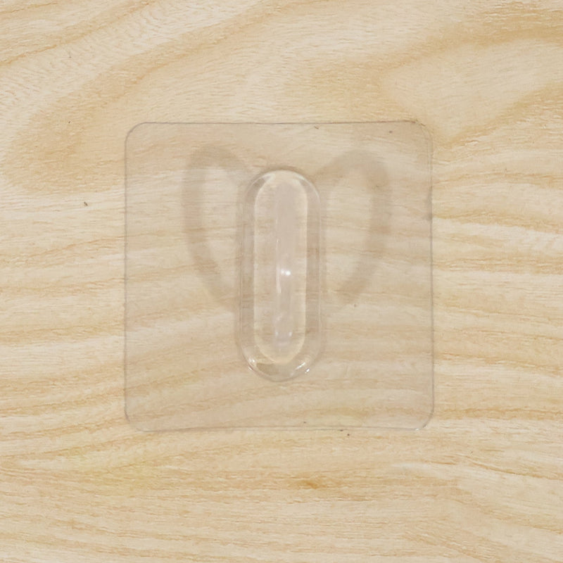 Close-up of transparent wall hook showing its adhesive pad