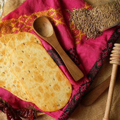 Crispy round Khakhra, a popular Indian healthy snack, displayed on a wooden surface.