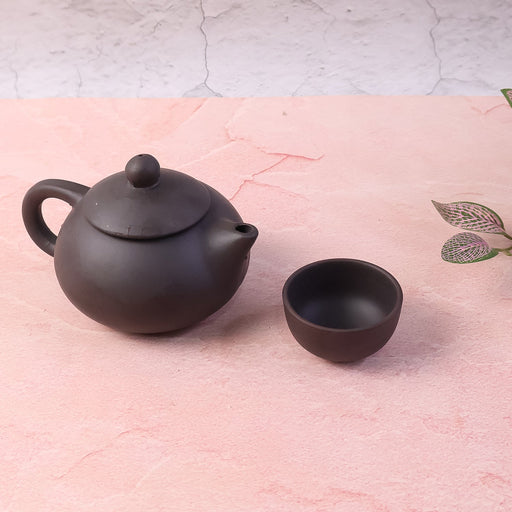 Matte black ceramic teapot and four matching cups in traditional oriental design