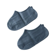 Silicone shoe cover with visible anti-skid sole pattern on a wet, tiled surface.
