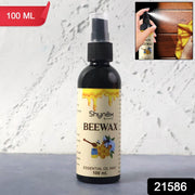 Spraying Beeswax Furniture Polish onto a wooden surface to nourish and protect the wood.