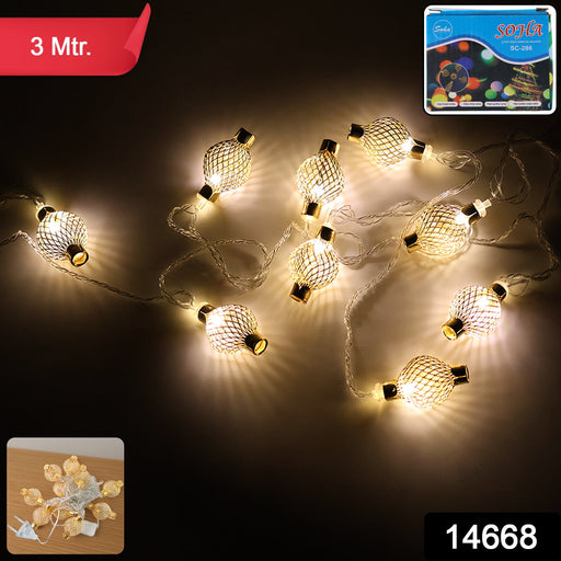 Close-up of decorative golden metal ball LED string light on plug-in wire